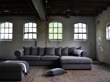 Corner sofa Juliette with loose back cushions and round armrests in a gray fabric