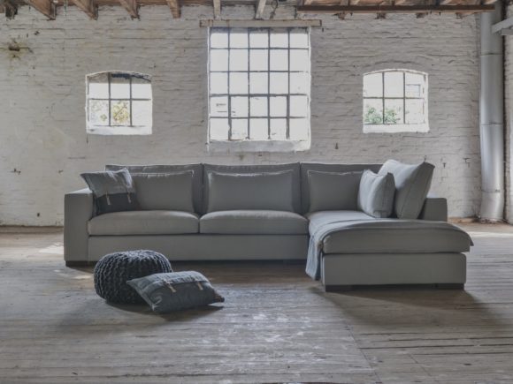 Corner sofa Annabelle with an ottoman element in a gray fabric and with lumbar cushions
