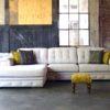 Aymee corner sofa with padded details in a light beige fabric with gray and yellow decorative cushions