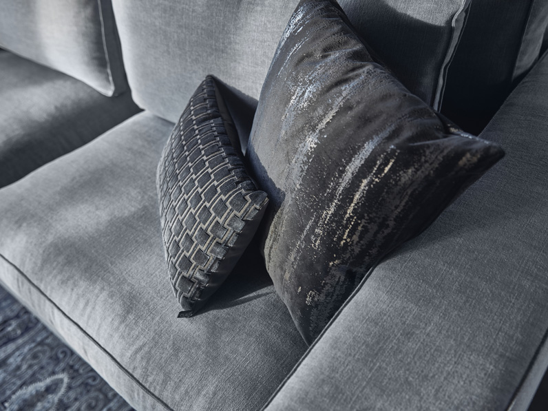Sofa Annabelle aus hellgrauem Stoff mit rechteckigem Teppich.