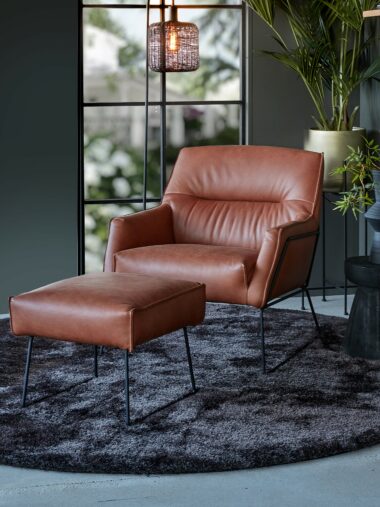Brown/cognac leather armchair rick breed with footstool and a round rug