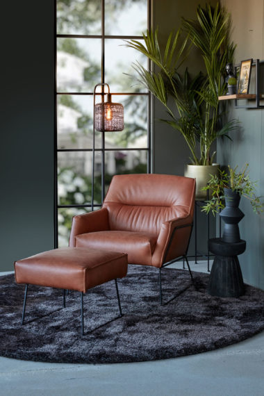 Brown/cognac leather armchair with footstool and a round rug