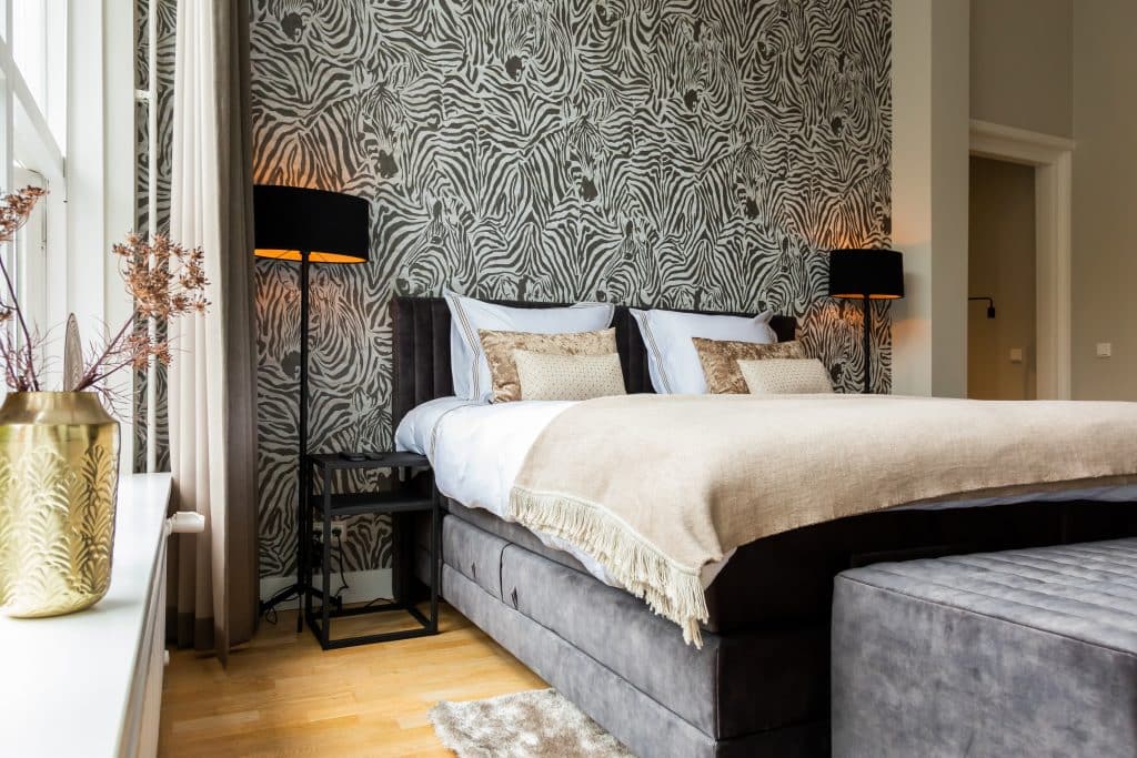Dark gray bed with zebra print wallpaper and a carpet