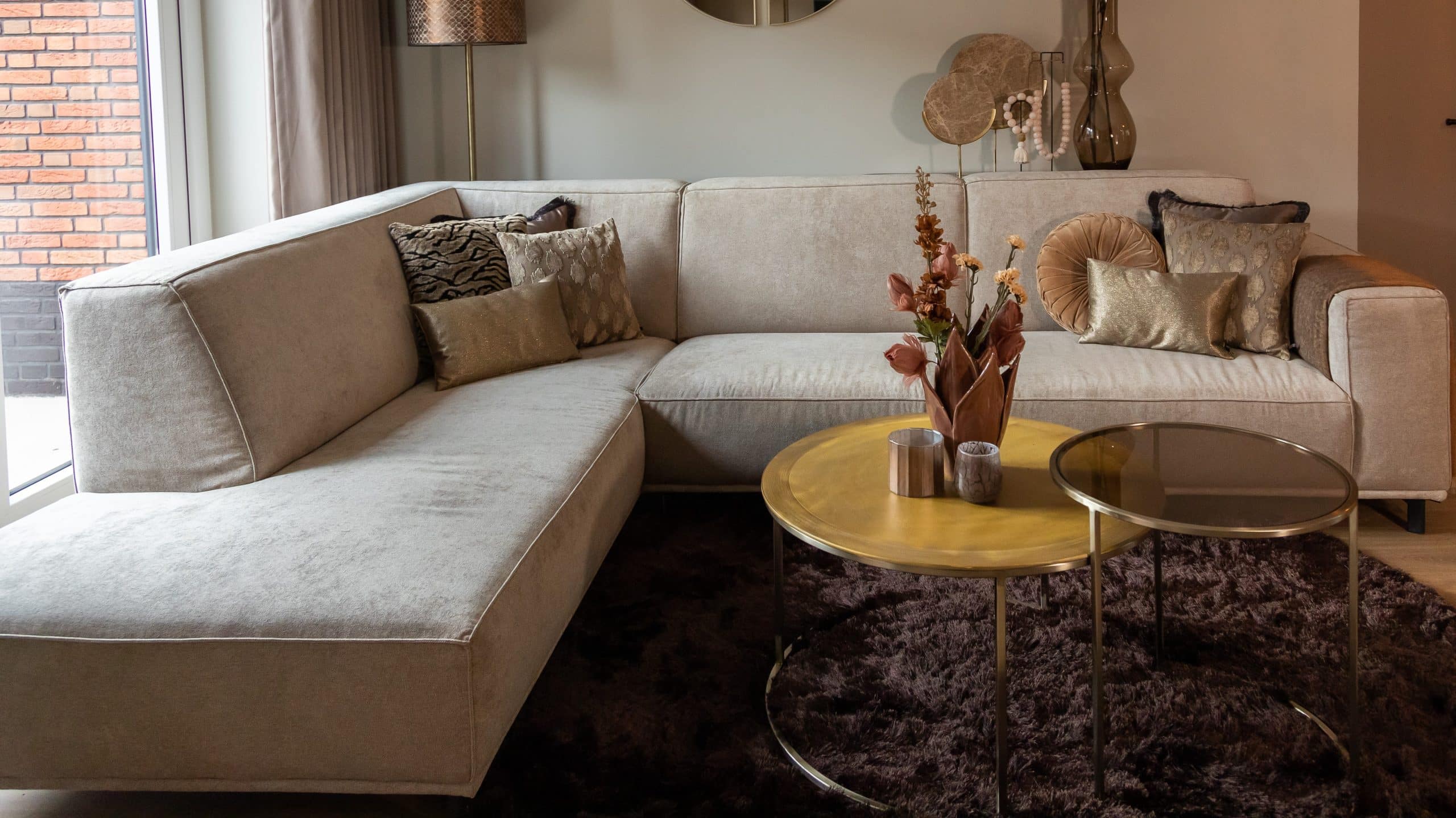 Inside view with corner sofa Sophie in a beige fabric and with a round rug.