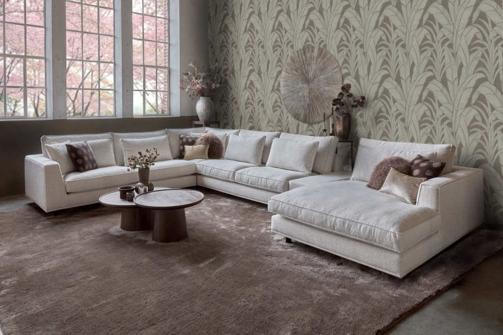 Ampio divano ad angolo in tessuto naturale leggero. Con decorazioni naturali e un grande tappeto.