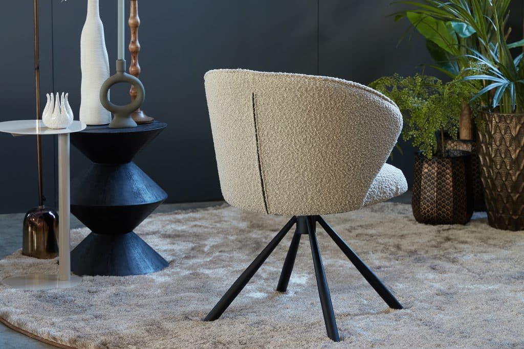 Boucle eetkamerstoel in een beige stof. Draaibaar op een zwarte spinpoot.