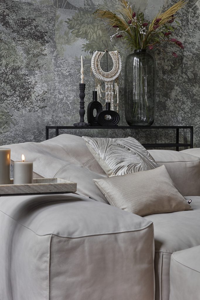 Coussins décoratifs et bougies LED sur canapé d'angle gris