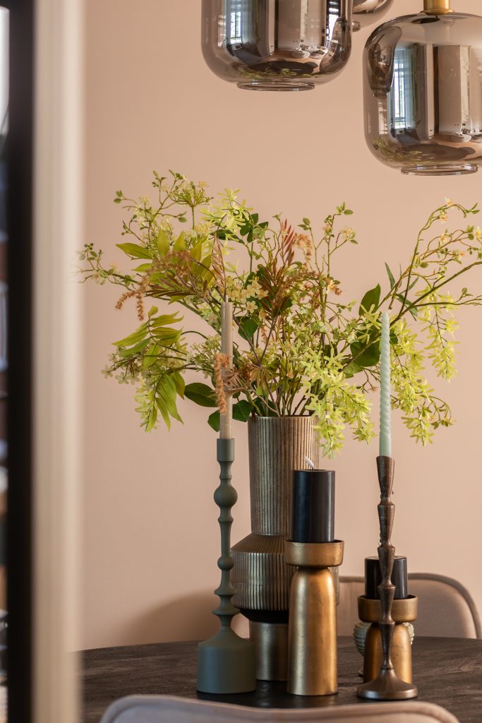 Vases with green branches and flowers in them