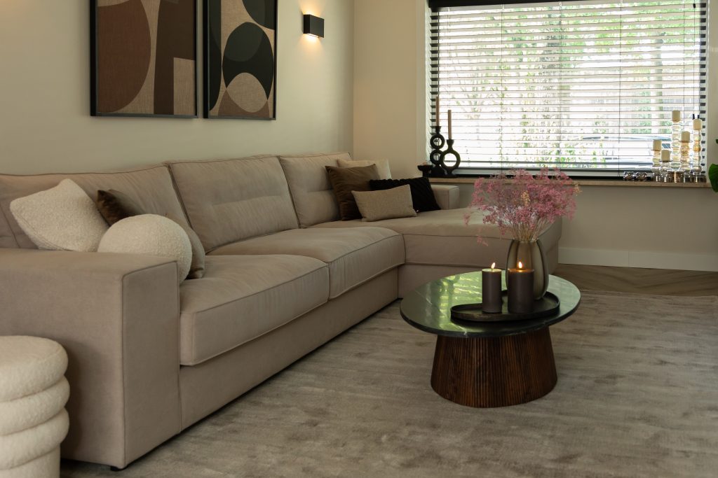 Beige corner sofa next to the window with brown oval coffee table
