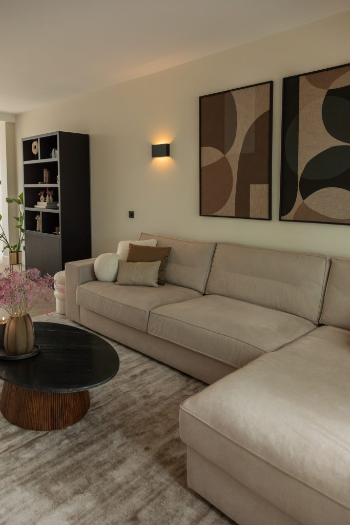 Divano angolare leggero con cuscini decorativi e quadri sopra il divano