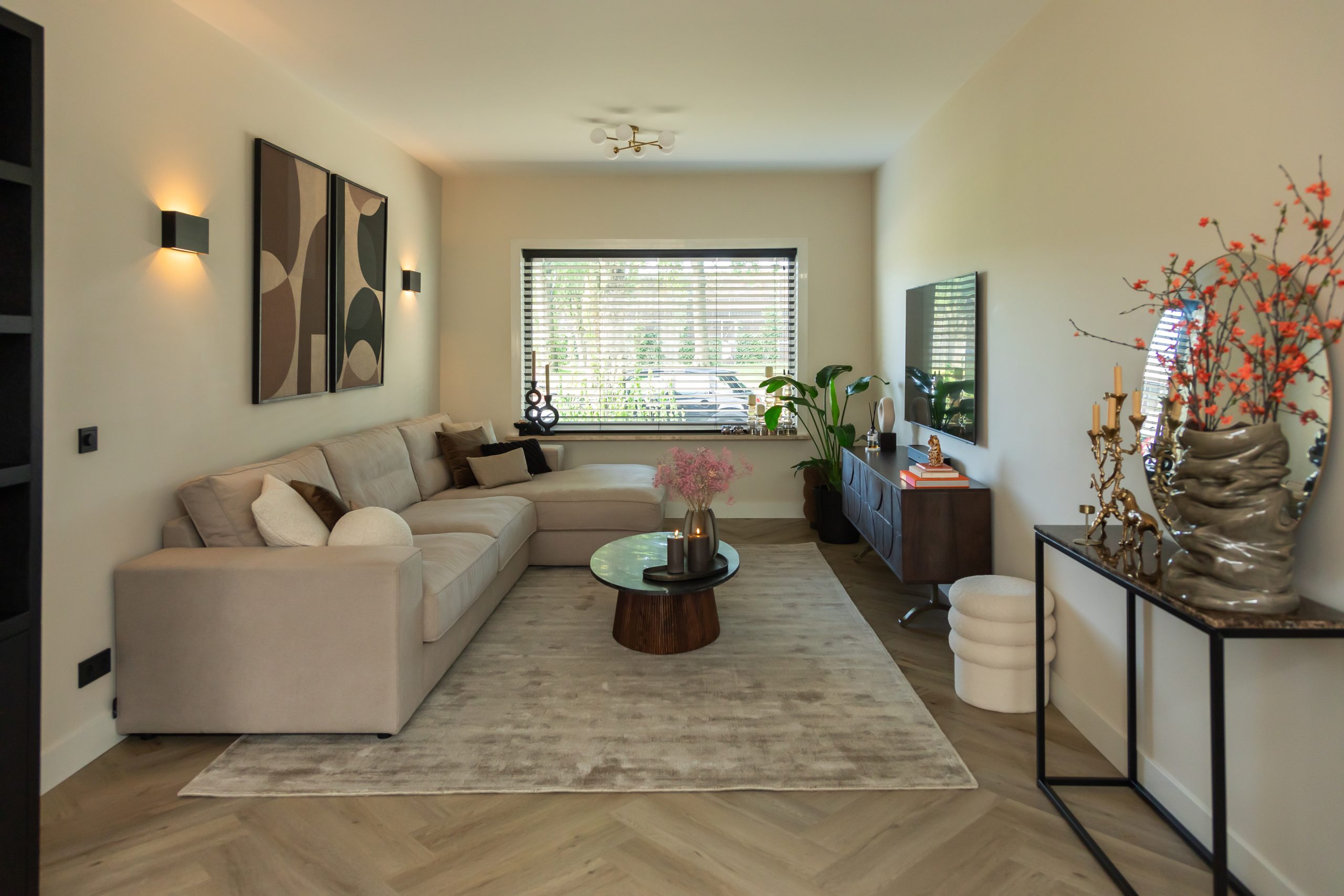 Celkový pohled na obývací pokoj se světlou rohovou pohovkou a tmavými doplňky
