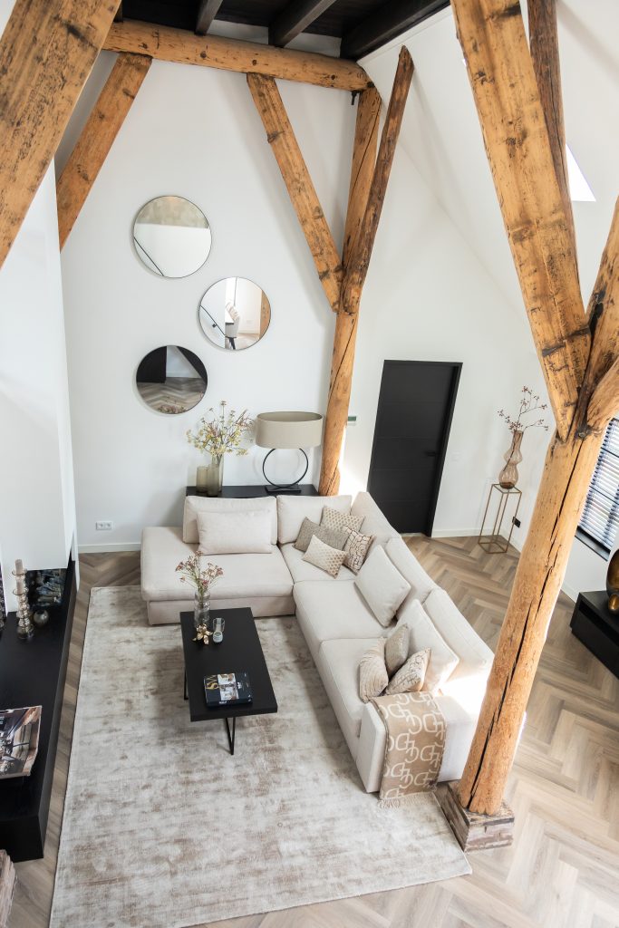 Fotografie obývacího pokoje s dřevěnými trámy a lehkou pohovkou.
