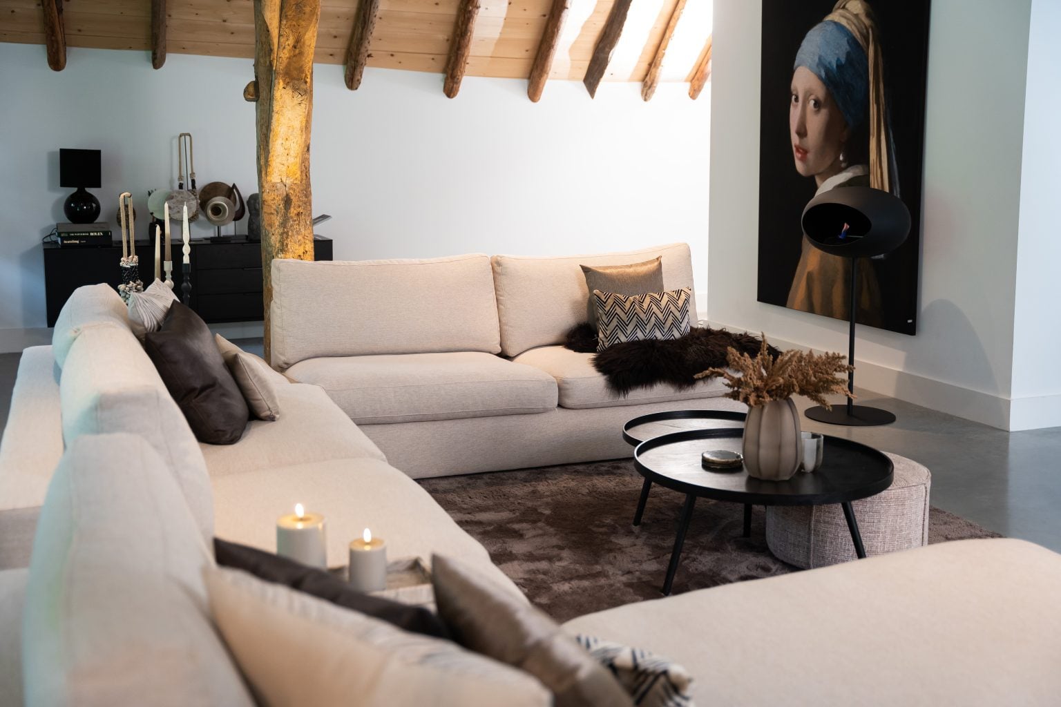 Grand canapé d'angle en forme de U avec un tapis sombre et des accessoires chics.