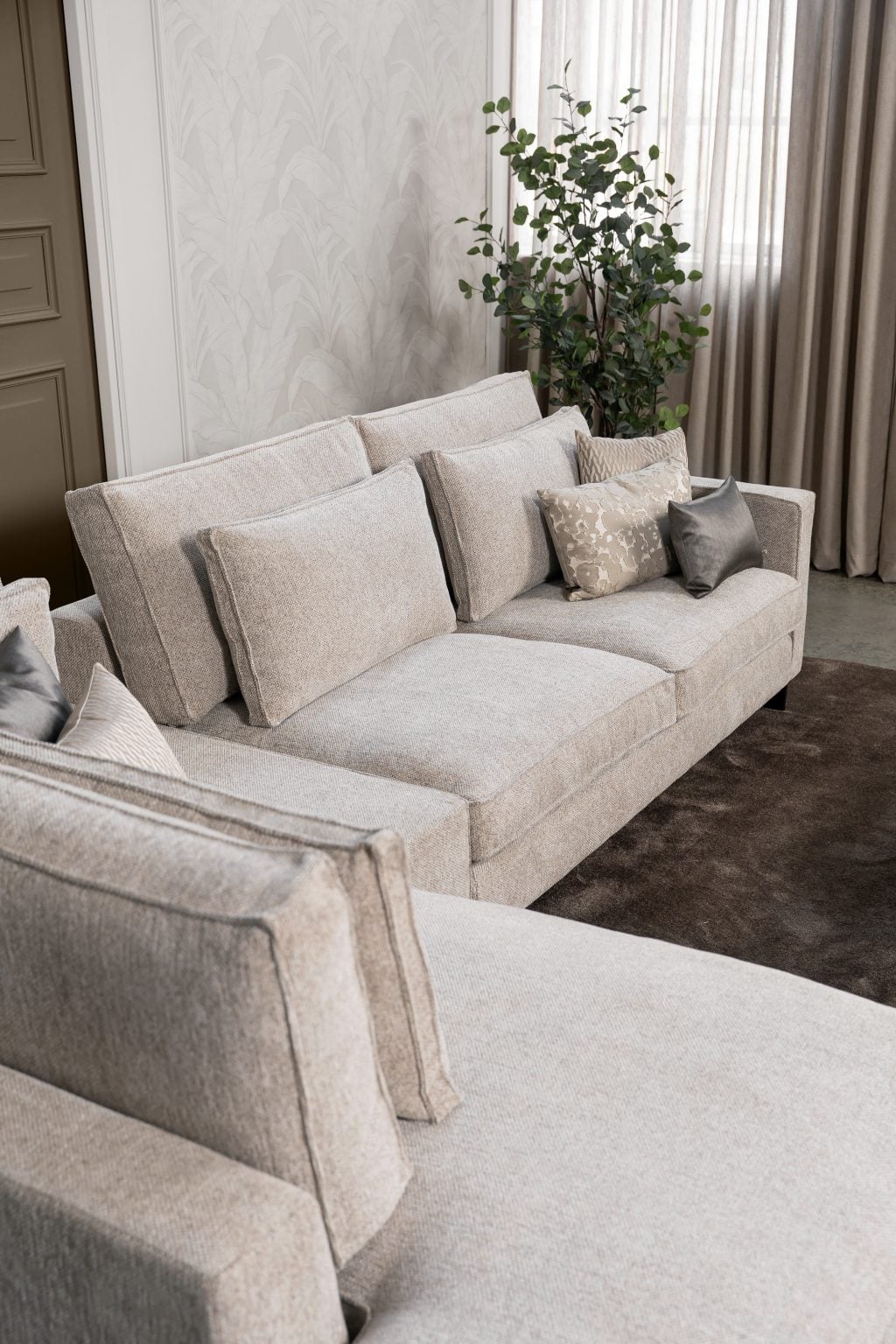 Ecksofa Gigi in einem neutralen Beigeton, mit Accessoires in warmen Erdtönen gestylt.
