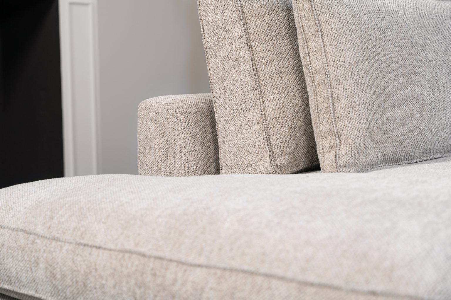 Hoekbank Gigi in een neutrale beige kleur, gestyled met accessoires in warme aardetinten.